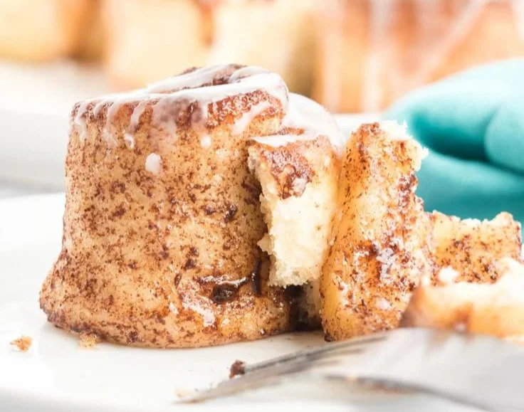 Freshly baked Air Fryer cinnamon rolls with icing, served on a plate.