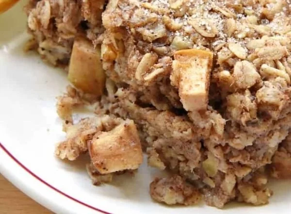 Bowl of healthy apple cinnamon baked oatmeal topped with fresh apple slices.