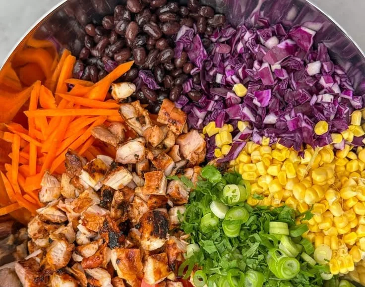 BBQ chicken salad with dense beans, fresh greens, and vibrant toppings.