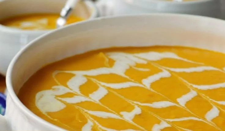 Bowl of delicious Carrot Apple Soup garnished with herbs