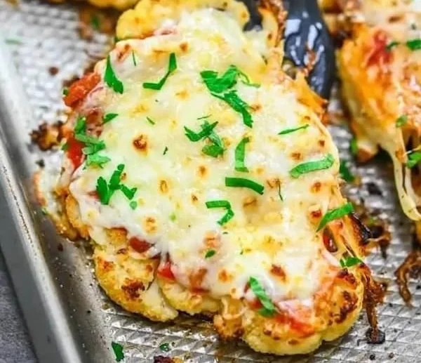 Cauliflower steaks served with marinara sauce on a white plate