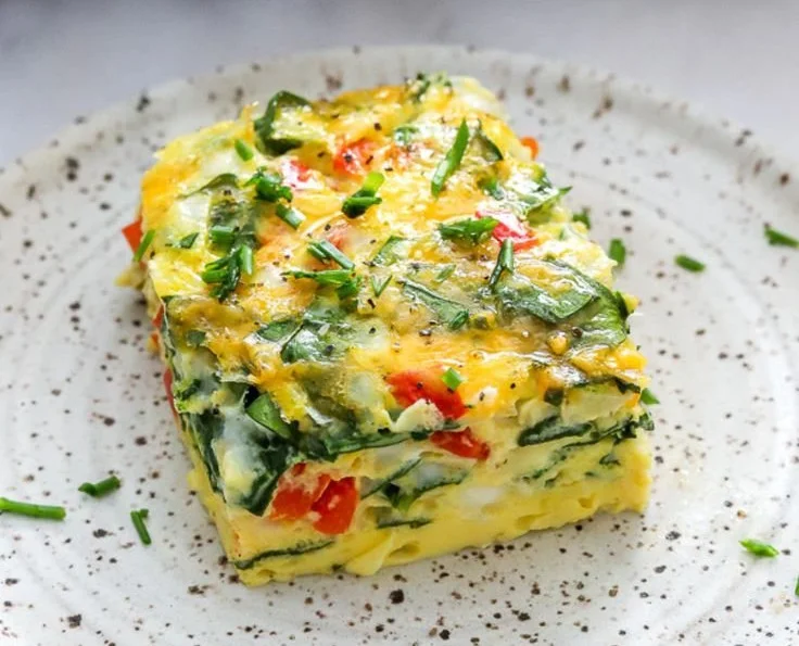 Cheesy protein-packed egg frittata served on a plate with fresh herbs.