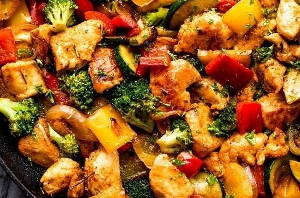 Chicken and vegetables skillet dish served in a pan with vibrant vegetables.