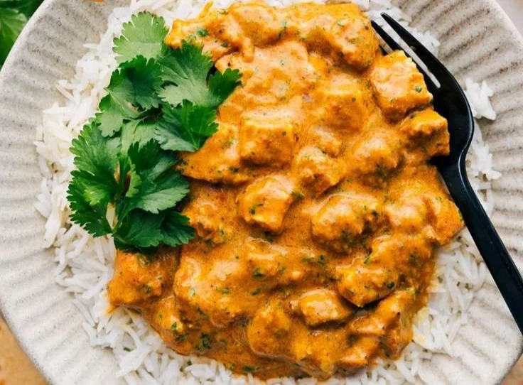 Delicious Crockpot Butter Chicken served with rice and garnished with cilantro.