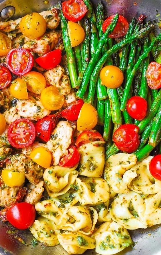 One-pan pesto chicken with tortellini and mixed vegetables in a vibrant dish.