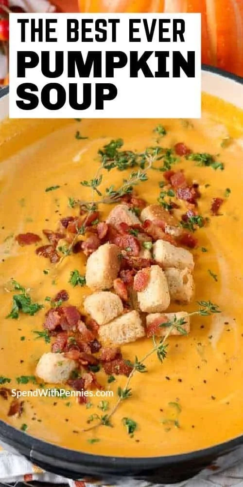 A bowl of creamy pumpkin soup garnished with herbs, perfect for fall.