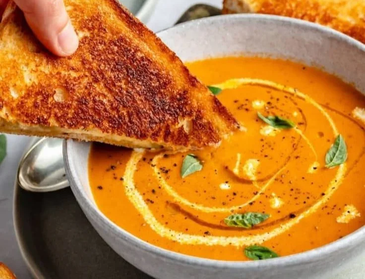 Bowl of homemade roasted tomato soup with fresh basil and seasoning