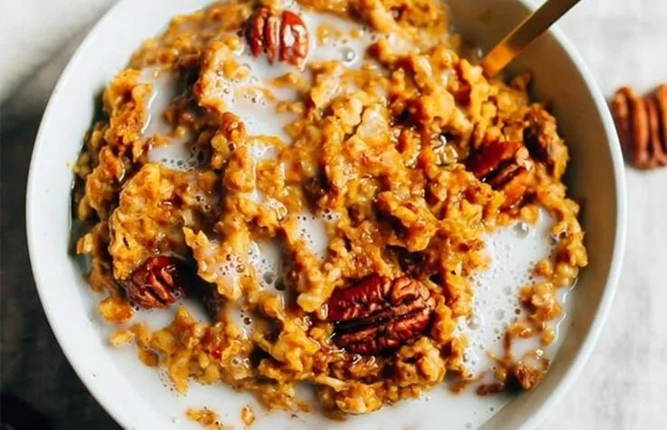 A bowl of slow cooker pumpkin pie oatmeal topped with spices and pumpkin seeds.