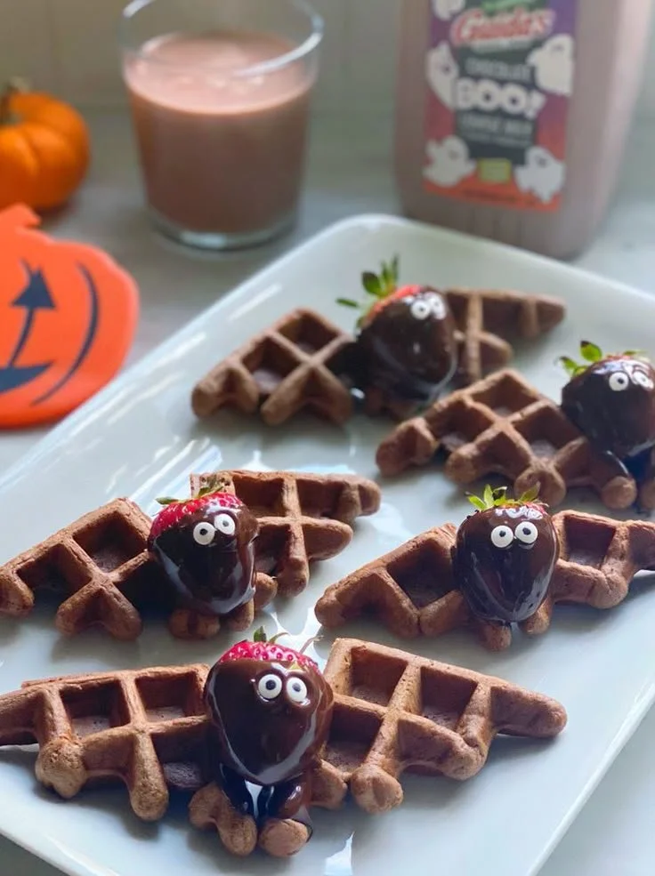 Fluffy chocolate milk waffles drizzled with syrup and topped with fresh berries