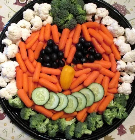 Colorful pumpkin veggie tray filled with assorted vegetables for Halloween party